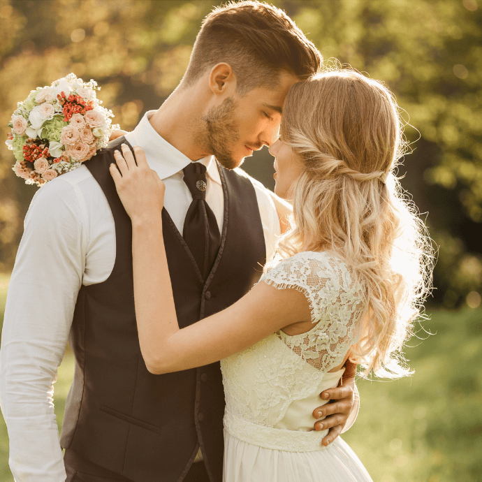 Newly weds in a loving embrace holding a bunch of flowers of grooms back - Camellio Wedding Planning and Events - Essex Wedding Planner